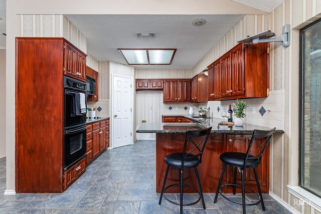 kitchen featuring sink, backsplash, a kitchen breakfast bar, black appliances, and kitchen peninsula