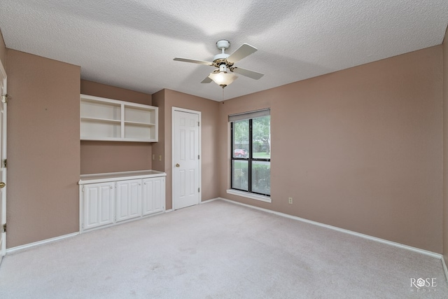 unfurnished bedroom featuring light colored carpet, a textured ceiling, ceiling fan, and a closet