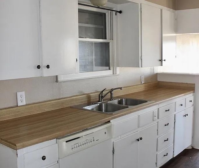 kitchen featuring white dishwasher, sink, and white cabinetry