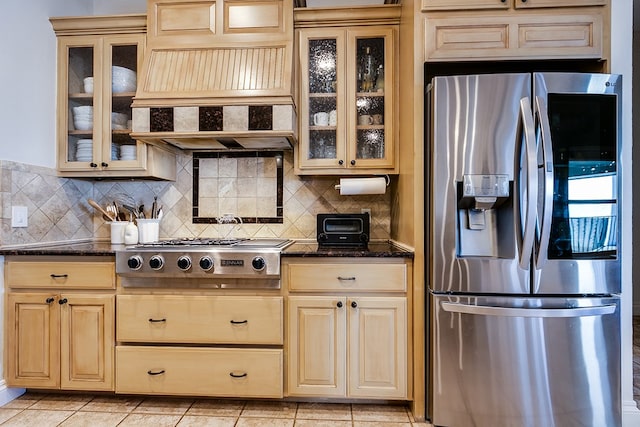 kitchen featuring dark stone countertops, light tile patterned floors, decorative backsplash, and stainless steel appliances