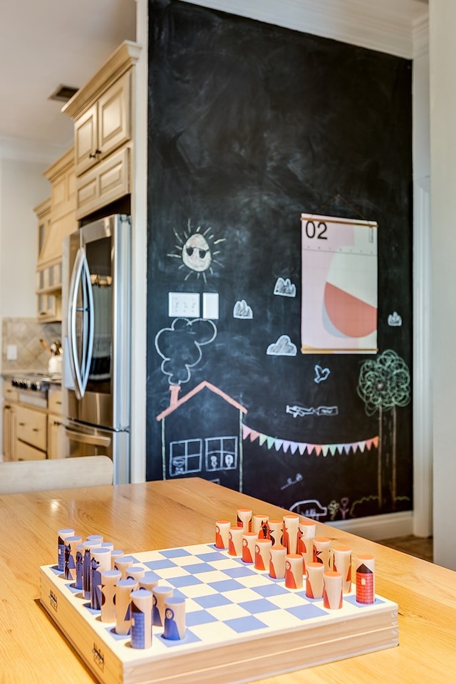 kitchen featuring ornamental molding, stainless steel refrigerator, and cream cabinetry