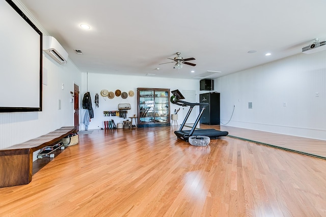 exercise room featuring hardwood / wood-style flooring, ceiling fan, and an AC wall unit