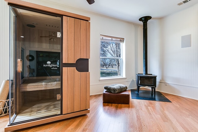 interior space featuring hardwood / wood-style floors, crown molding, wood walls, and a wood stove