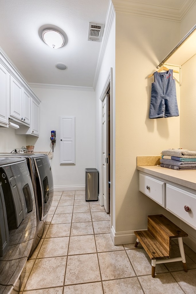 laundry room featuring light tile patterned floors, crown molding, washing machine and dryer, and cabinets