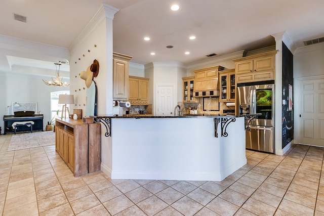 kitchen featuring crown molding, stainless steel fridge with ice dispenser, a kitchen breakfast bar, kitchen peninsula, and decorative backsplash