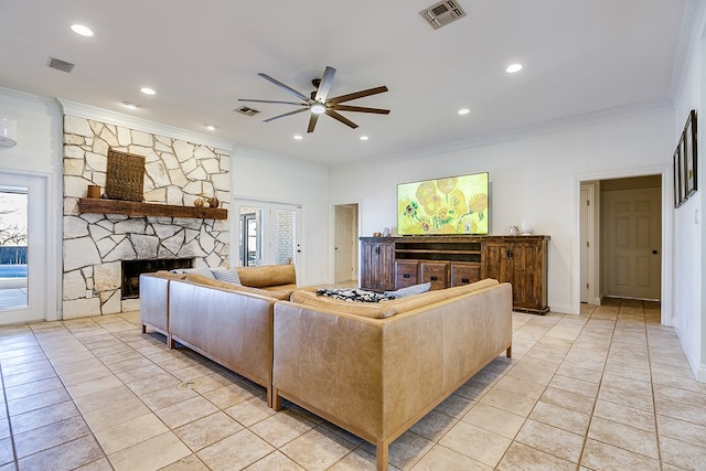 tiled living room with ornamental molding, a stone fireplace, and ceiling fan