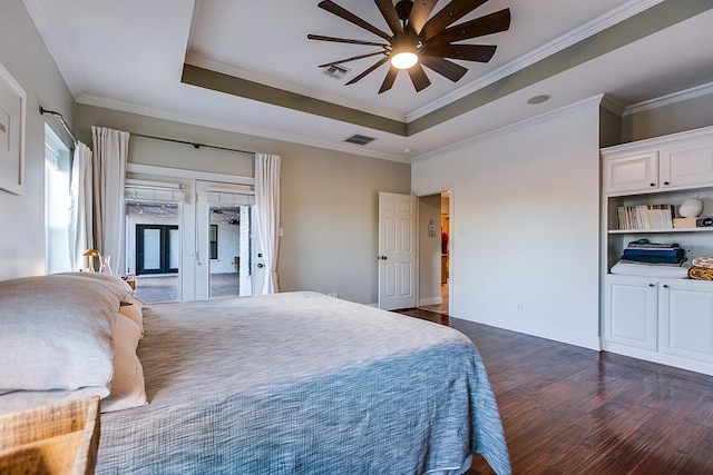 bedroom featuring dark wood-type flooring, ceiling fan, ornamental molding, and a tray ceiling