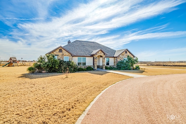 705 Ratliff Rd, Wall, TX 76904 - view of front of house featuring stone siding, a chimney, and a playground