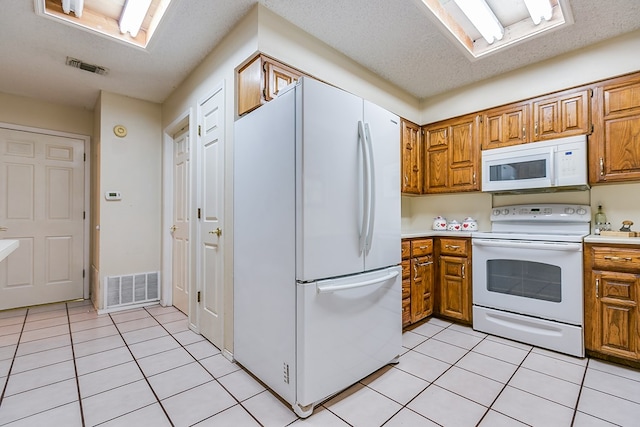 kitchen with light tile patterned floors, white appliances, and a textured ceiling