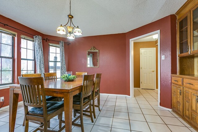 tiled dining room featuring an inviting chandelier and a textured ceiling