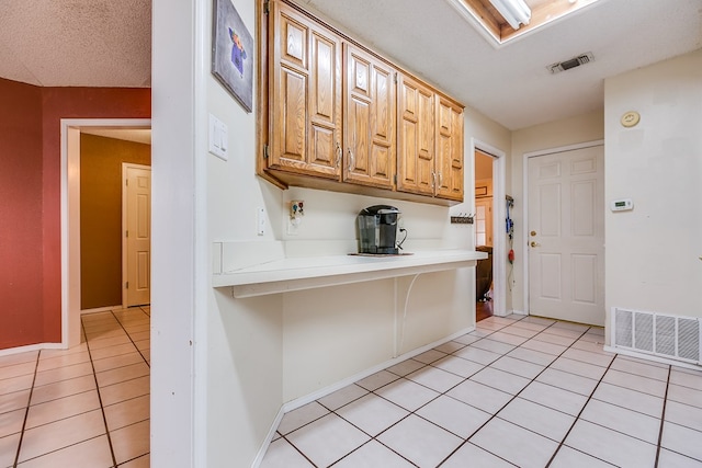 kitchen featuring light tile patterned floors, a kitchen breakfast bar, a textured ceiling, and light brown cabinets