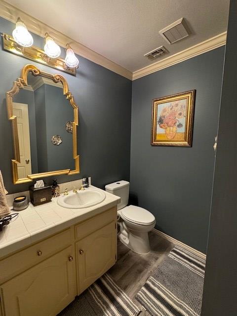 bathroom with vanity, crown molding, wood-type flooring, and toilet