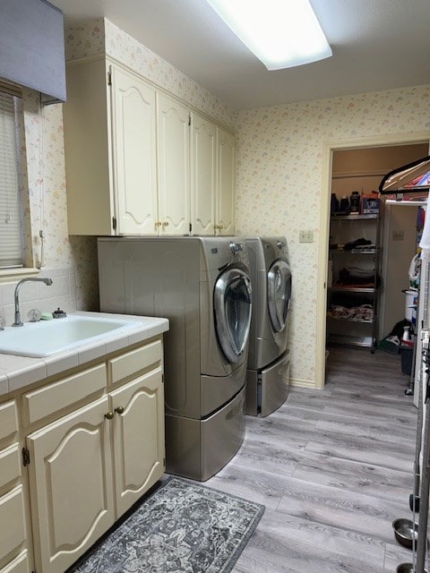 washroom with independent washer and dryer, cabinets, sink, and light hardwood / wood-style flooring