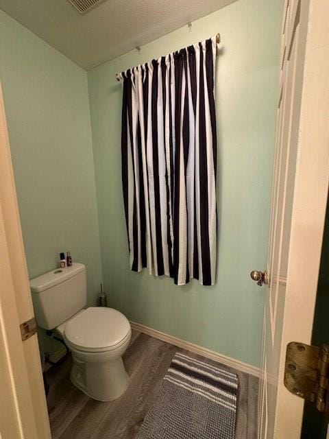 bathroom with hardwood / wood-style floors and toilet