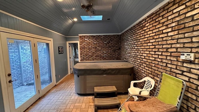 interior space featuring ornamental molding, brick wall, lofted ceiling with skylight, and wooden ceiling