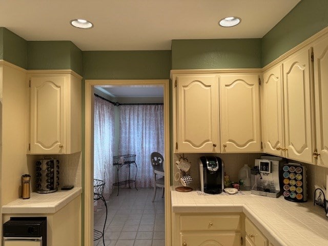 kitchen with tile counters, light tile patterned floors, decorative backsplash, and white cabinets