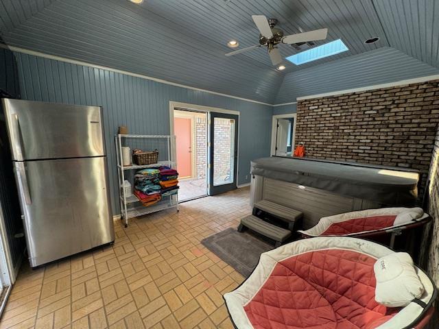 interior space featuring ceiling fan, vaulted ceiling with skylight, and wood ceiling