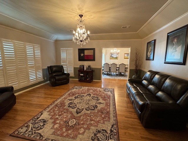 living room featuring hardwood / wood-style flooring, crown molding, and a chandelier