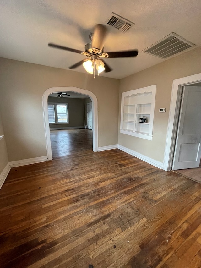 unfurnished room with ceiling fan, dark wood-type flooring, and built in features