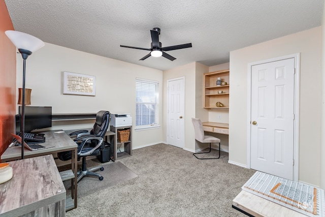 office featuring ceiling fan, built in desk, light carpet, and a textured ceiling