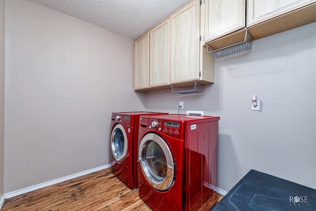 laundry area featuring hardwood / wood-style flooring, cabinets, washing machine and dryer, and a textured ceiling