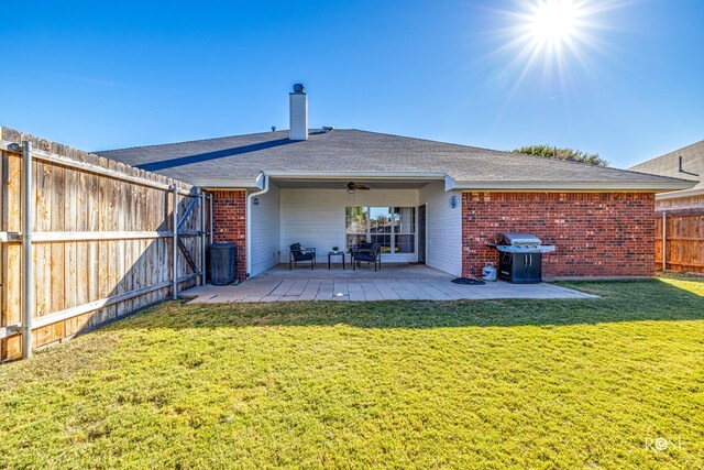 back of property with ceiling fan, a yard, and a patio area