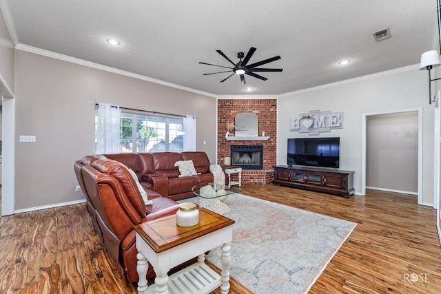 living room featuring ceiling fan, wood-type flooring, a textured ceiling, and ornamental molding