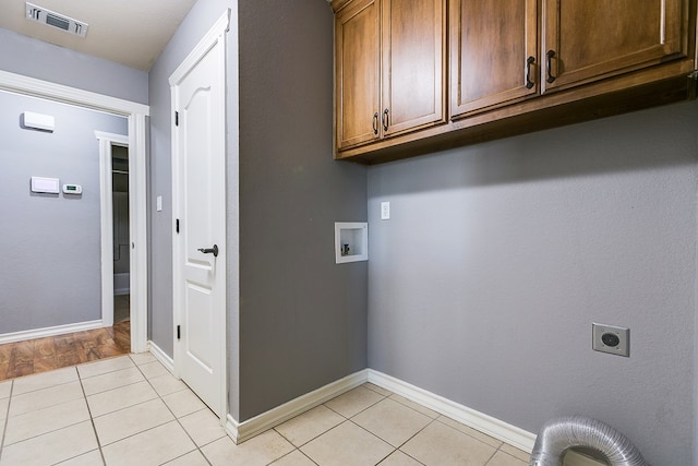 washroom with washer hookup, cabinets, hookup for an electric dryer, and light tile patterned flooring