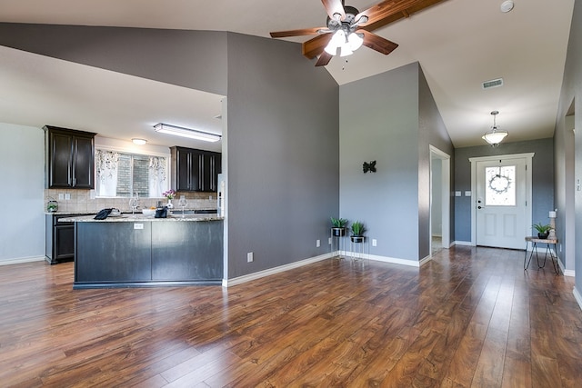 kitchen with tasteful backsplash, lofted ceiling, dark hardwood / wood-style flooring, light stone countertops, and dark brown cabinets