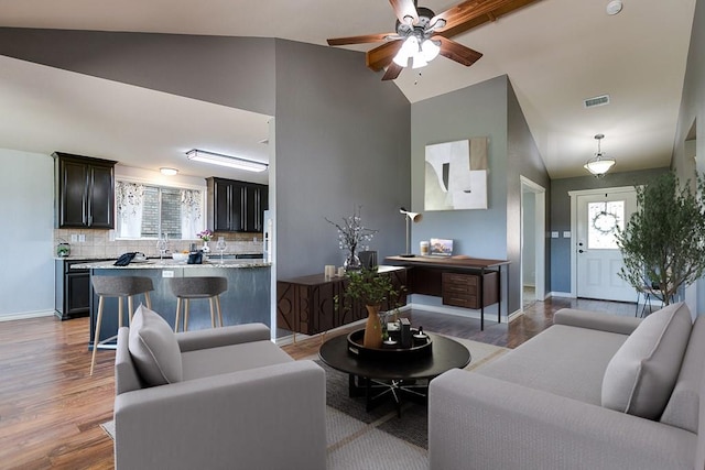 living room featuring a healthy amount of sunlight, sink, vaulted ceiling, and light wood-type flooring