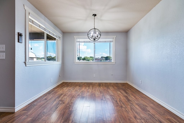 unfurnished room with dark hardwood / wood-style flooring and a notable chandelier