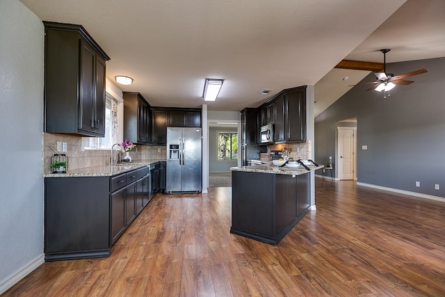 kitchen with sink, vaulted ceiling, dark hardwood / wood-style flooring, stainless steel appliances, and light stone countertops