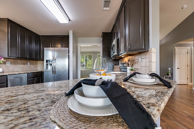 kitchen featuring dark brown cabinetry, light stone countertops, stainless steel appliances, and dark hardwood / wood-style floors