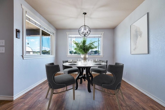 dining area with dark wood-type flooring and a notable chandelier