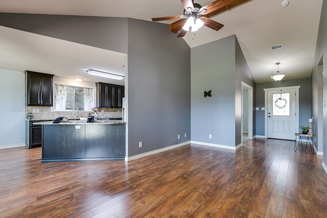 kitchen featuring tasteful backsplash, dark hardwood / wood-style flooring, light stone countertops, and vaulted ceiling