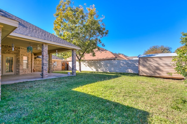 view of yard featuring a patio, ceiling fan, and a storage unit