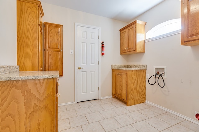 clothes washing area featuring cabinets, washer hookup, and light tile patterned floors