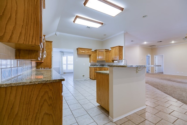 kitchen with a breakfast bar, backsplash, ornamental molding, kitchen peninsula, and light carpet