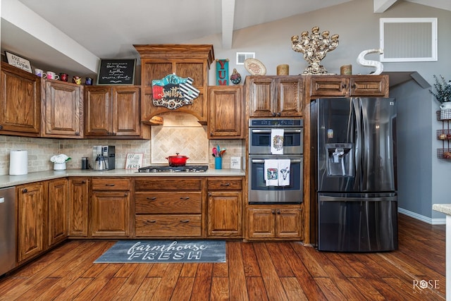 kitchen featuring vaulted ceiling with beams, decorative backsplash, dark wood-type flooring, and appliances with stainless steel finishes