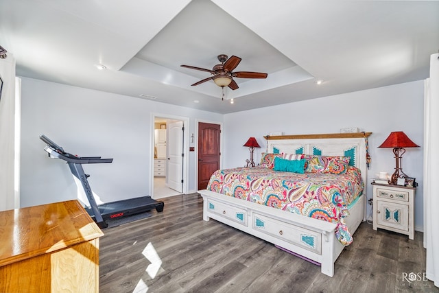 bedroom with connected bathroom, dark hardwood / wood-style floors, a raised ceiling, and ceiling fan