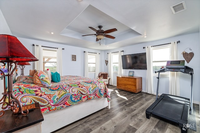 bedroom with multiple windows, a tray ceiling, ceiling fan, and hardwood / wood-style flooring