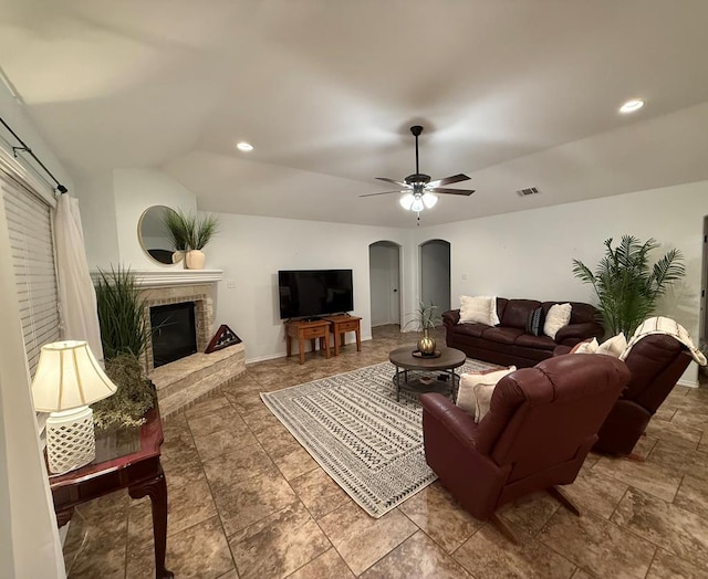 living room featuring vaulted ceiling, ceiling fan, and a fireplace