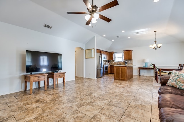 living room featuring vaulted ceiling, sink, and ceiling fan with notable chandelier