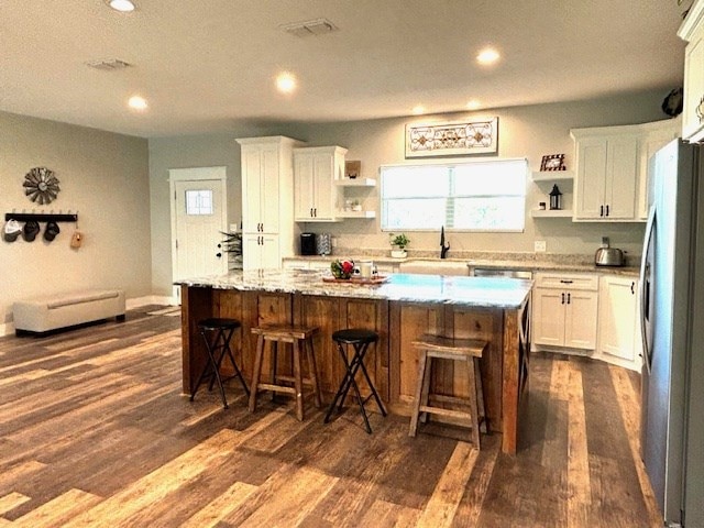 110 Vick Dr, Brownwood, TX 76801 - kitchen featuring white cabinetry, stainless steel fridge, a breakfast bar area, and a center island
