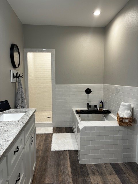 110 Vick Dr, Brownwood, TX 76801 - bathroom with vanity, wood-type flooring, tile walls, and a bathing tub