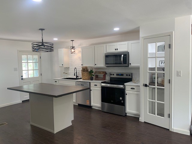 1619 Canal Rd, San Angelo, TX 76904 - kitchen with stainless steel appliances, dark wood-type flooring, tasteful backsplash, white cabinetry, and recessed lighting