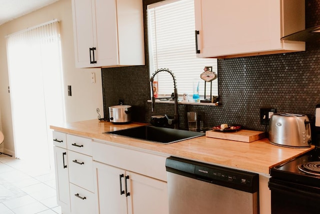 kitchen with light tile patterned flooring, tasteful backsplash, white cabinetry, dishwasher, and sink