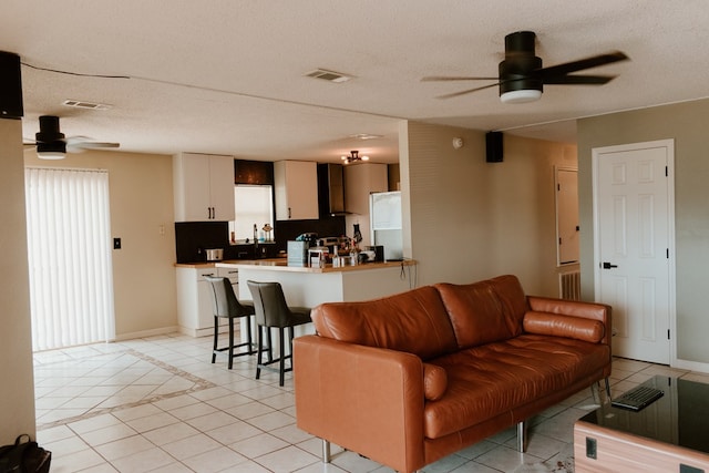 living room with ceiling fan, a textured ceiling, and light tile patterned floors