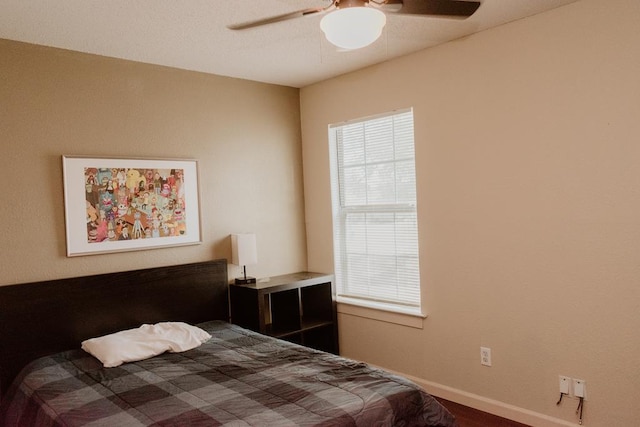 bedroom featuring ceiling fan, hardwood / wood-style floors, and multiple windows