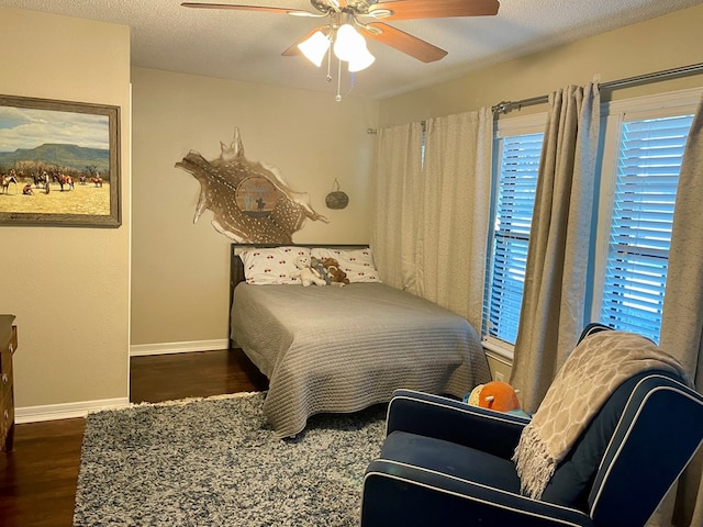 bedroom with ceiling fan, dark hardwood / wood-style flooring, and a textured ceiling